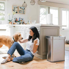 58L rectangular sensor bin with voice and motion control - brushed stainless steel - lifestyle woman and dog image